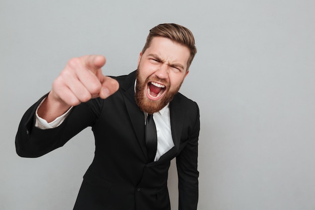 Hombre de negocios enojado en traje gritando y señalando con el dedo