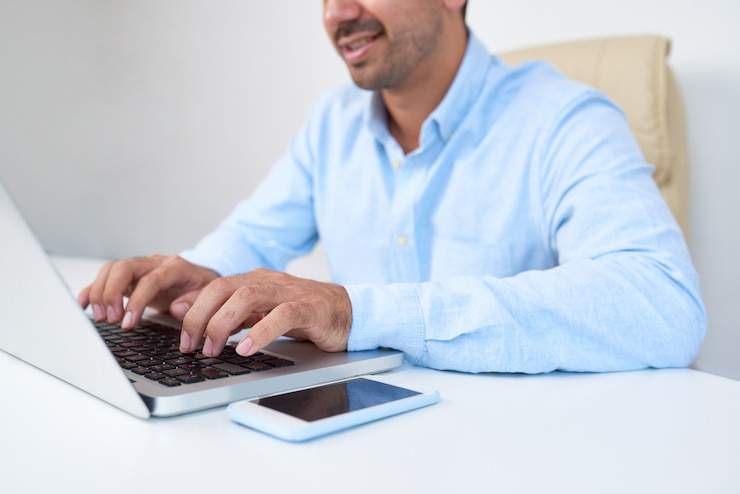 Foto gratuito un hombre de negocios escribiendo en una computadora portátil.