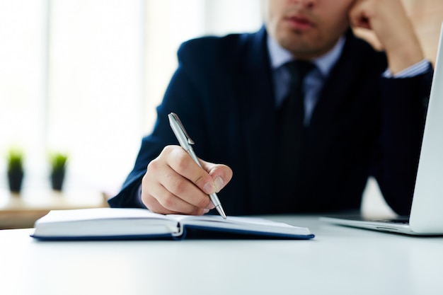 Hombre de negocios escribiendo en cuaderno diario