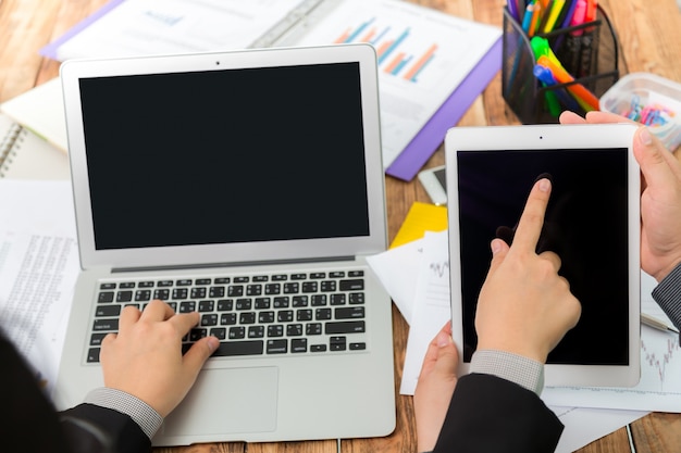 Hombre de negocios escribiendo en un portátil y señalando una tablet