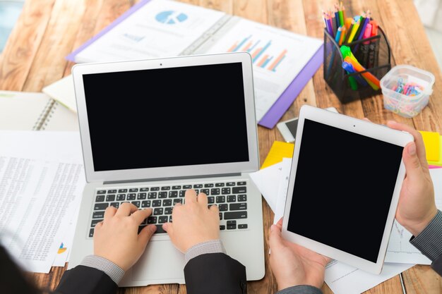 Hombre de negocios escribiendo en un portátil y con una tablet al lado