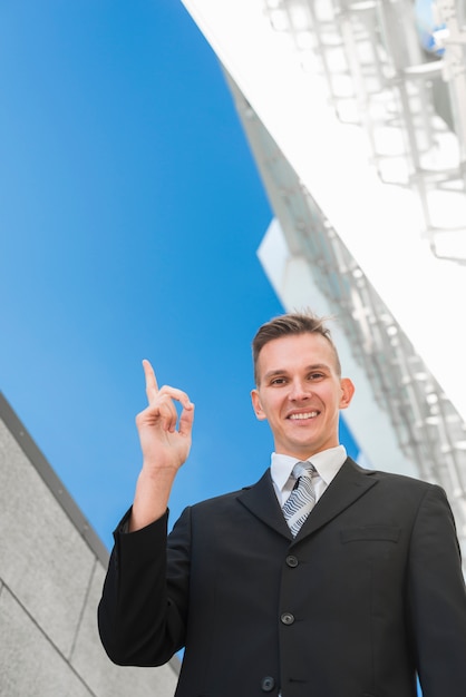 Foto gratuita hombre de negocios con estilo apuntando hacia arriba