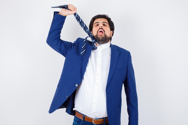 Hombre de negocios estirando la corbata en traje formal y mirando exhausto, vista frontal.