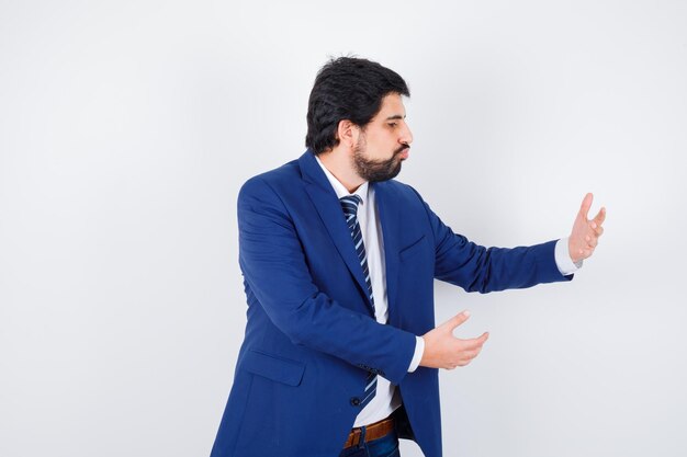 Hombre de negocios estirando una mano como sosteniendo algo en traje formal y mirando serio. vista frontal.