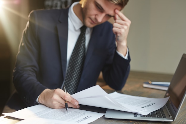 Foto gratuita hombre de negocios estresado que trabaja con documentos contractuales