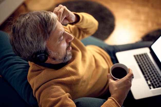 Hombre de negocios exhausto sosteniendo su cabeza con dolor mientras trabajaba hasta tarde en casa