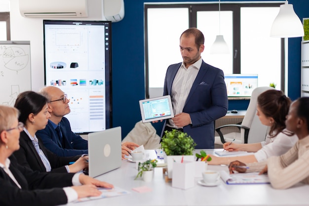 Hombre de negocios exitoso que presenta la buena evolución de la empresa mediante tableta digital