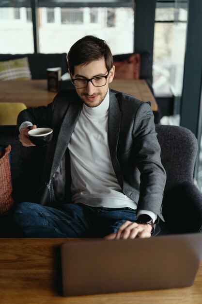 Hombre de negocios exitoso trabajando en la computadora portátil mientras bebe café