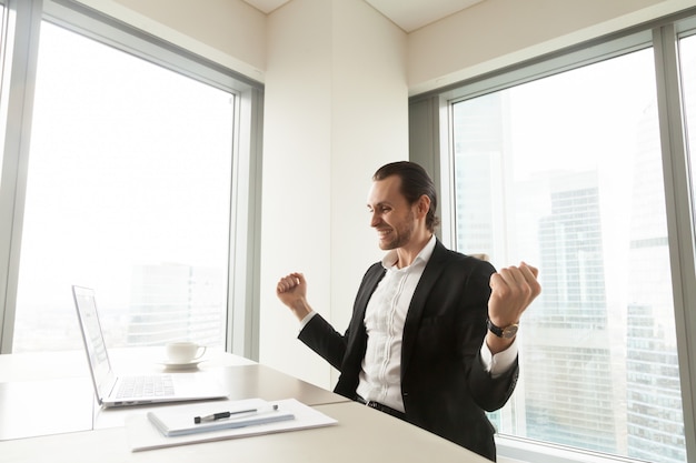 Hombre de negocios feliz delante de la computadora portátil