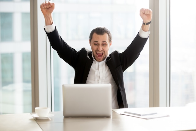 Foto gratuita hombre de negocios feliz delante de la computadora portátil