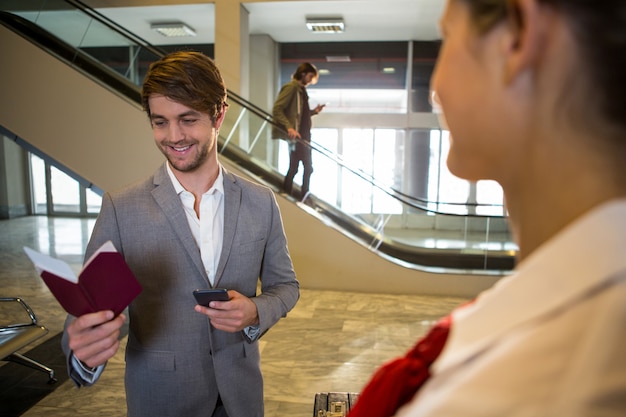 Hombre de negocios feliz mirando su pasaporte mientras está de pie