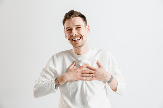 Hombre de negocios feliz de pie, sonriendo aislado en el espacio gris. Hermoso retrato masculino de medio cuerpo. Joven, satisfacer, hombre