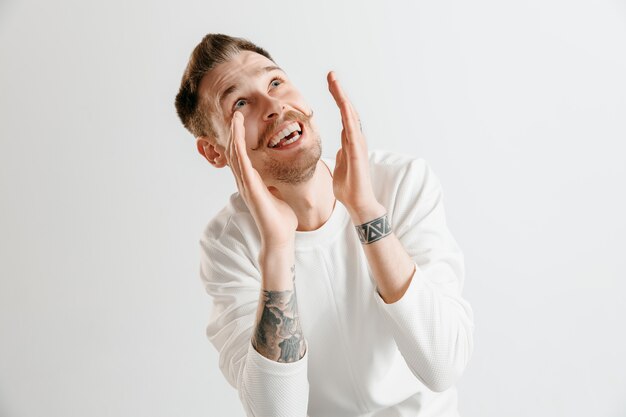 Hombre de negocios feliz de pie, sonriendo aislado en estudio gris