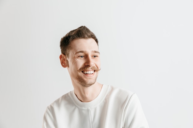 Hombre de negocios feliz de pie, sonriendo aislado en estudio gris