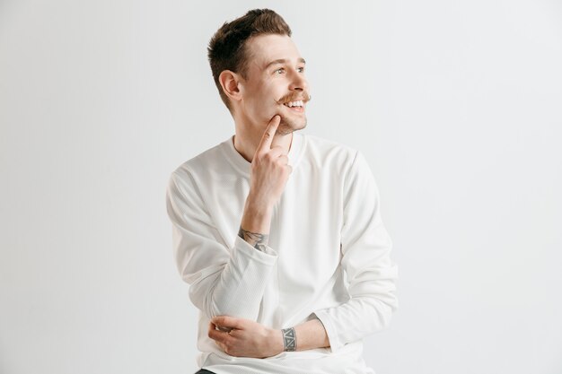 Hombre de negocios feliz de pie, sonriendo aislado en estudio gris