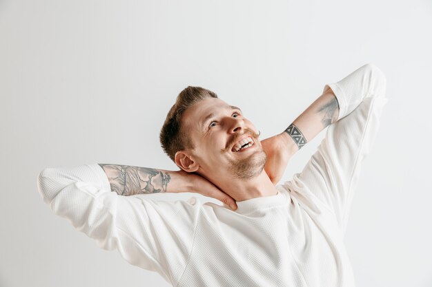 Hombre de negocios feliz de pie, sonriendo aislado en estudio gris