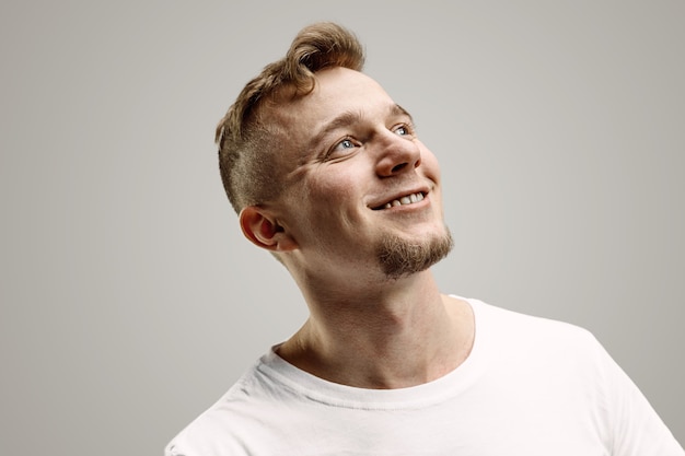 Hombre de negocios feliz de pie, sonriendo aislado sobre fondo gris de estudio. Hermoso retrato masculino de medio cuerpo. Joven satisface al hombre. Las emociones humanas, el concepto de expresión facial.