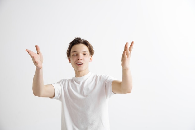 Hombre de negocios feliz de pie, sonriendo aislado sobre fondo gris de estudio. Hermoso retrato masculino de medio cuerpo. Joven satisface al hombre. Las emociones humanas, el concepto de expresión facial.