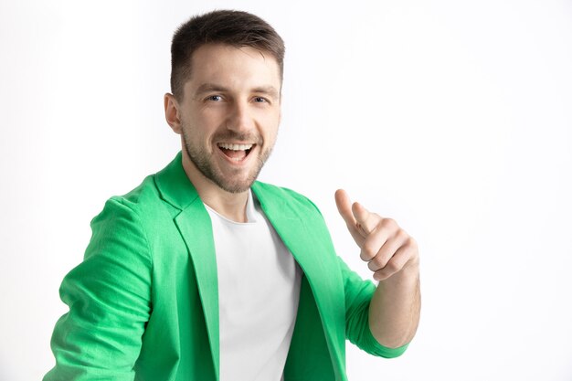 Hombre de negocios feliz de pie, sonriendo y apuntando a la cámara aislada en el estudio gris.