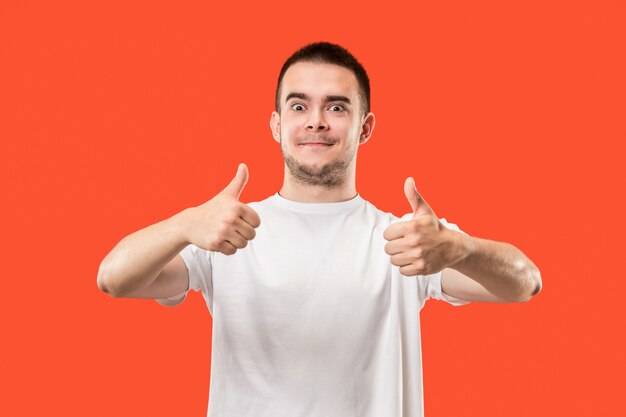 El hombre de negocios feliz de pie y sonriendo contra el espacio rojo.