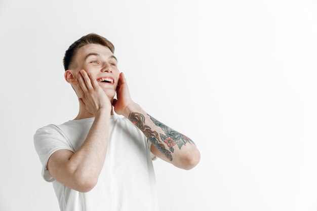 El hombre de negocios feliz de pie y sonriendo contra la pared gris.