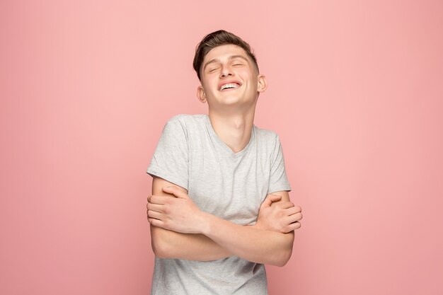 El hombre de negocios feliz de pie y sonriente contra el espacio de color rosa.