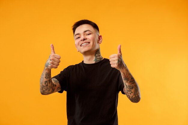 El hombre de negocios feliz de pie y sonriente contra naranja.