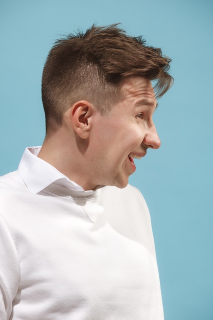 Hombre de negocios feliz de pie y sonriente contra la pared del estudio.