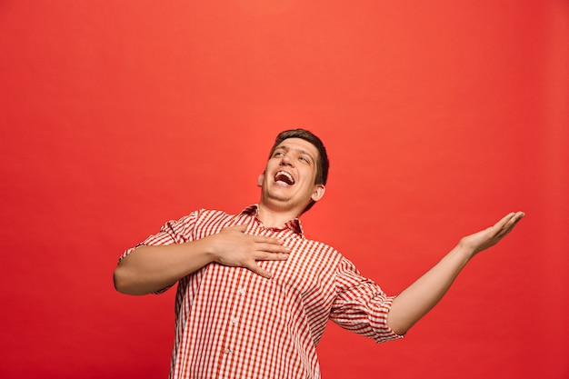 Hombre de negocios feliz de pie y sonriente contra la pared roja.