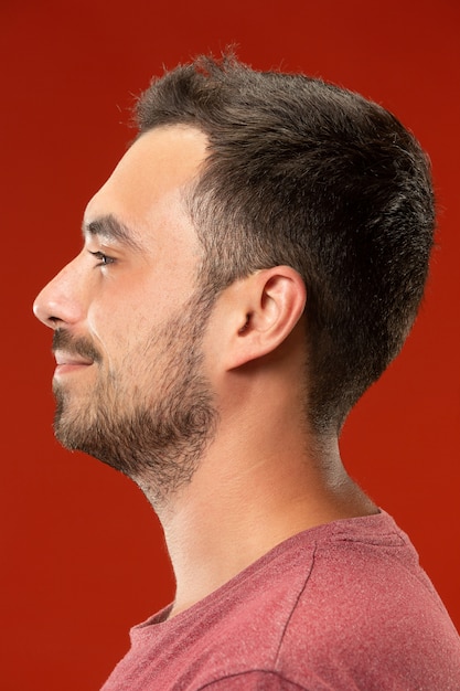 Foto gratuita el hombre de negocios feliz de pie y sonriente contra la pared roja.