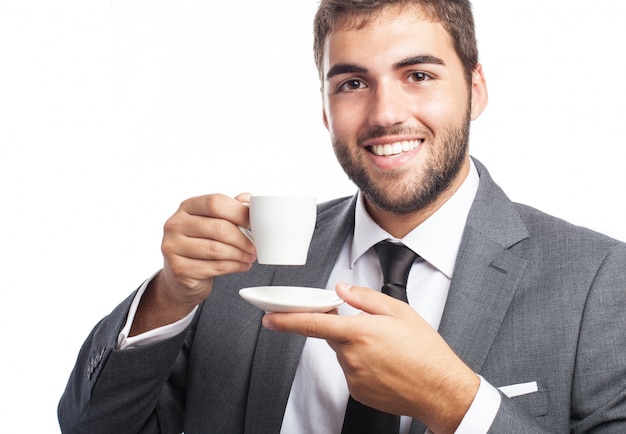 Hombre de negocios feliz posando con una taza y un platillo
