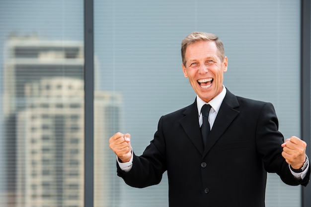 Hombre de negocios feliz que mira la cámara cerca del edificio