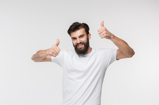 El hombre de negocios feliz que se opone y que sonríe contra blanco.