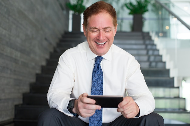 Hombre de negocios feliz que practica surf Internet en smartphone