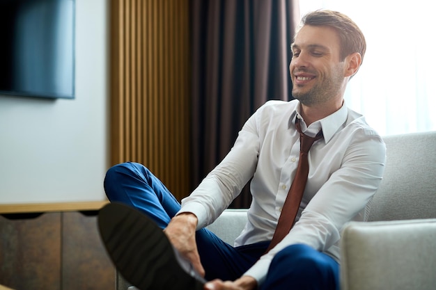 Un hombre de negocios feliz quitándose los zapatos en una habitación de hotel