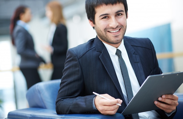 Hombre de negocios feliz sentado con un sujetapapeles