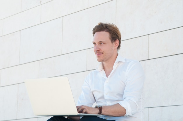 Hombre de negocios feliz trabajando en la computadora portátil al aire libre