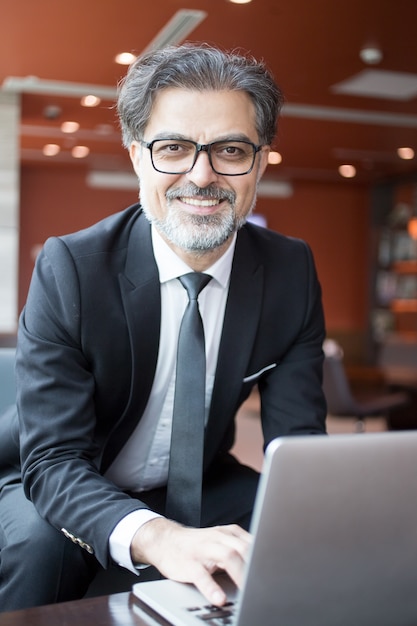 Hombre de negocios feliz trabajando en la computadora portátil en el vestíbulo