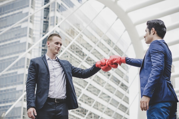 Foto gratuita hombre de negocios con los guantes de boxeo rojos listos para luchar a su compañero de trabajo.