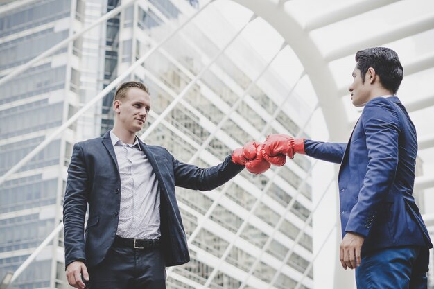 Hombre de negocios con los guantes de boxeo rojos listos para luchar a su compañero de trabajo.