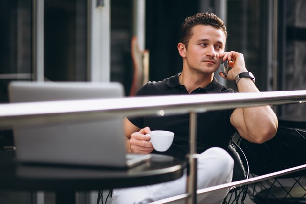 Hombre de negocios guapo en un café con computadora portátil