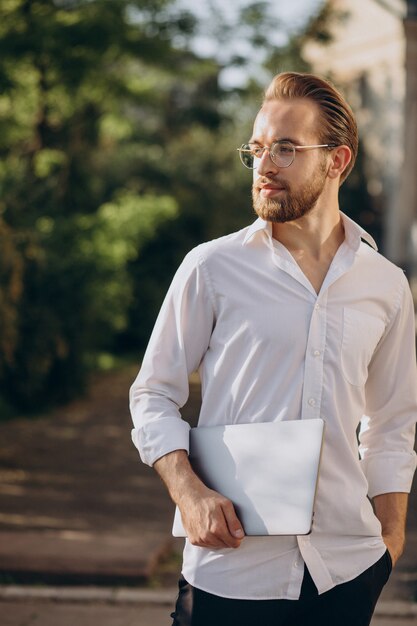 Hombre de negocios guapo caminando con laptop