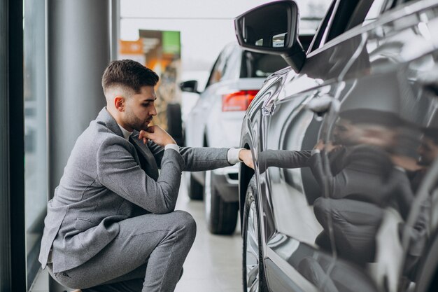 Hombre de negocios guapo elegir un automóvil en una sala de exposición de automóviles