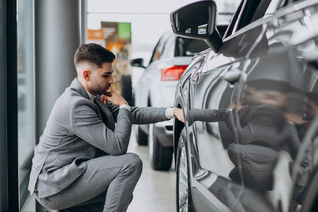 Hombre de negocios guapo elegir un automóvil en una sala de exposición de automóviles