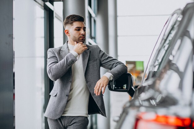 Hombre de negocios guapo elegir un automóvil en una sala de exposición de automóviles