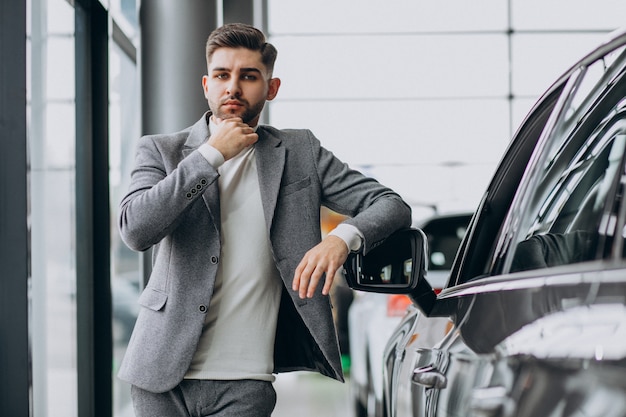 Hombre de negocios guapo elegir un automóvil en una sala de exposición de automóviles