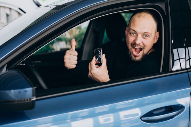 Hombre de negocios guapo eligiendo un coche en una sala de exposición de coches