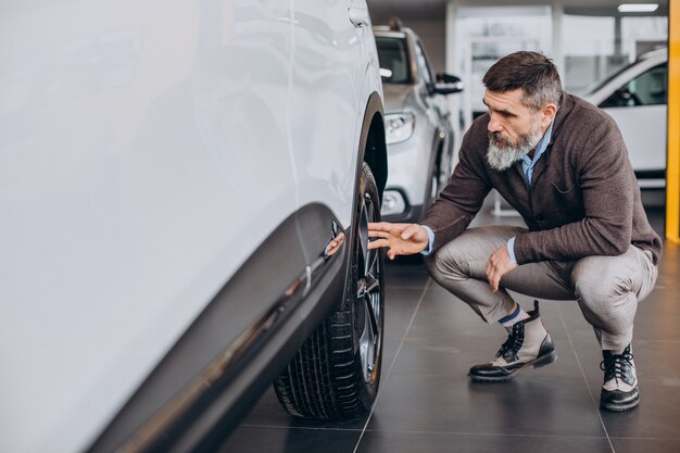 Hombre de negocios guapo eligiendo un coche en la sala de exposición de coches