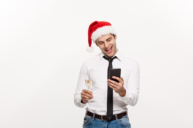 Hombre de negocios guapo hablando por teléfono y sosteniendo una copa de champán celebrando la Navidad