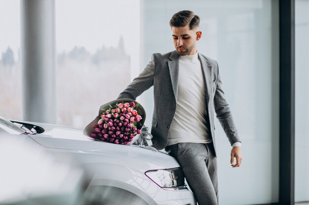 Hombre de negocios guapo joven que entrega ramo de flores hermosas